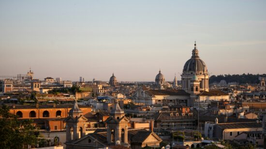 Golden hour bathes Rome’s sea of domes and bell towers, stretching toward the horizon in warm haze.